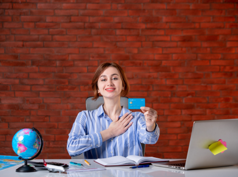 Happy woman holding flight tickets at desk